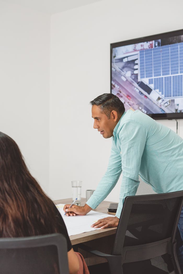 The Art of Drawing Readers In: Your attractive post title goes here Two professionals in an office setting discuss a solar panel project, fostering business collaboration.